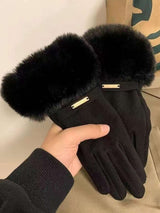 Black gloves with fur cuffs held by a hand against a neutral background