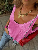Person wearing a pink top and gold necklace with a blurred background