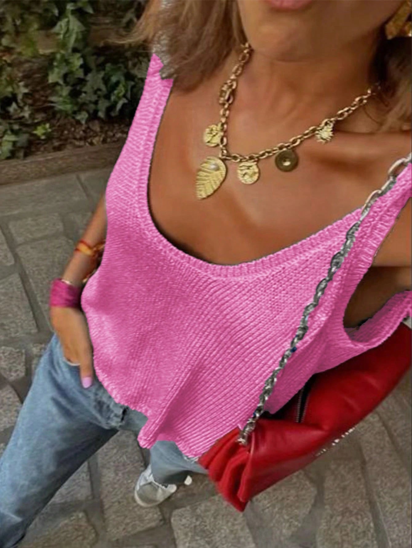 Person wearing a pink top and gold necklace with a blurred background