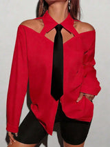 Red blouse with cut-out design and black tie against a plain background