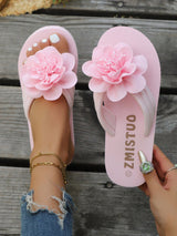 Pink sandals with floral designs on a wooden floor