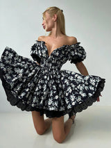 Woman wearing a black floral off-shoulder dress on a white background