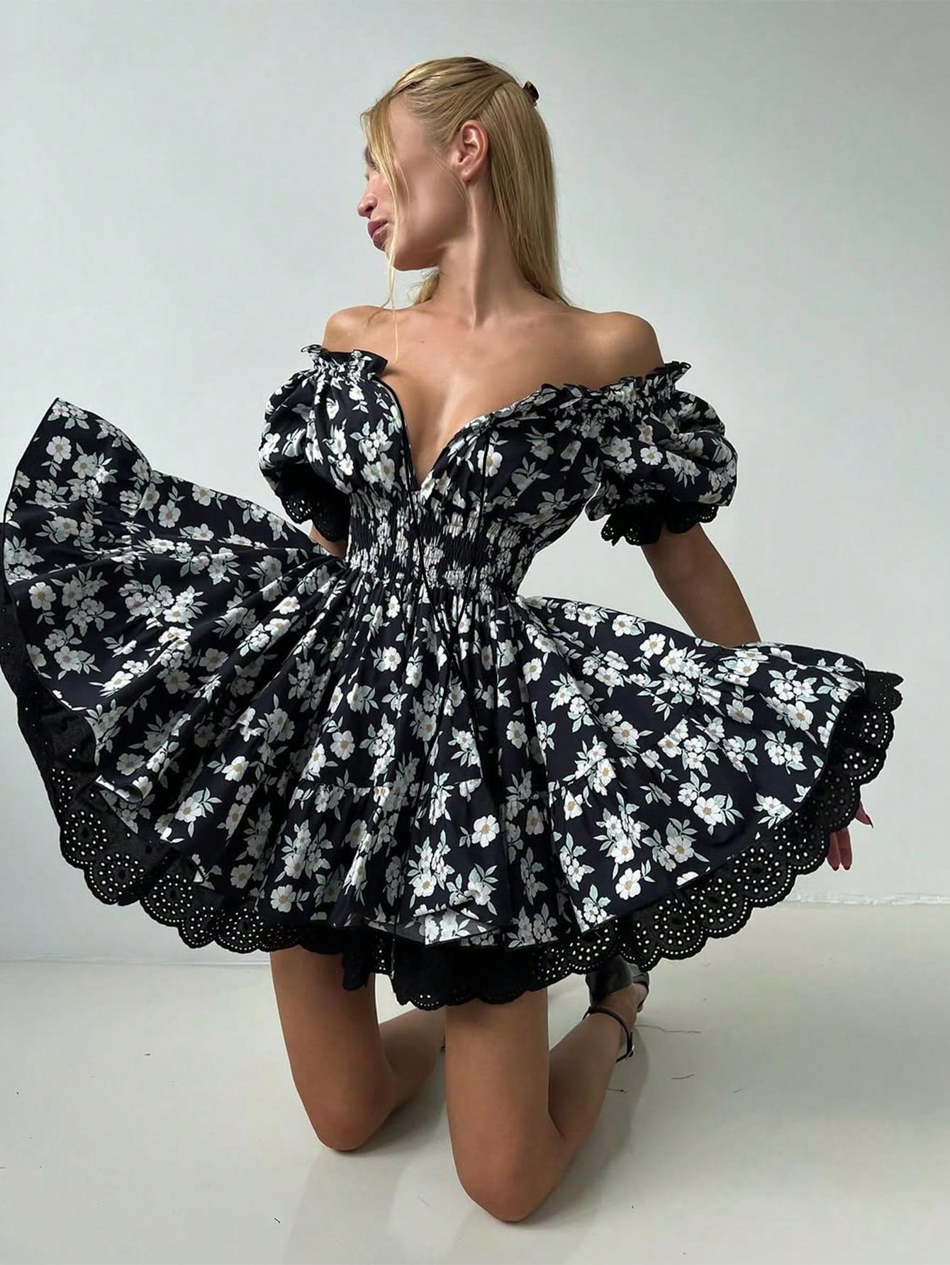 Woman wearing a black floral off-shoulder dress on a white background