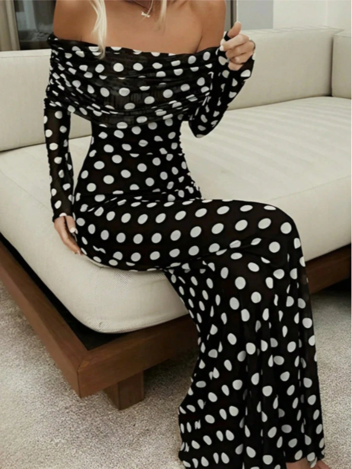 Person wearing a black polka dot outfit sitting on a couch.