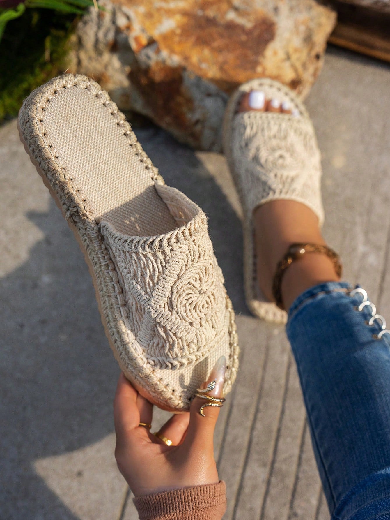 Close-up of a woven sandal held by a hand with a blurred background