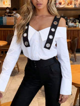 Person wearing a white off-shoulder top with black straps and buttons in a cafe setting