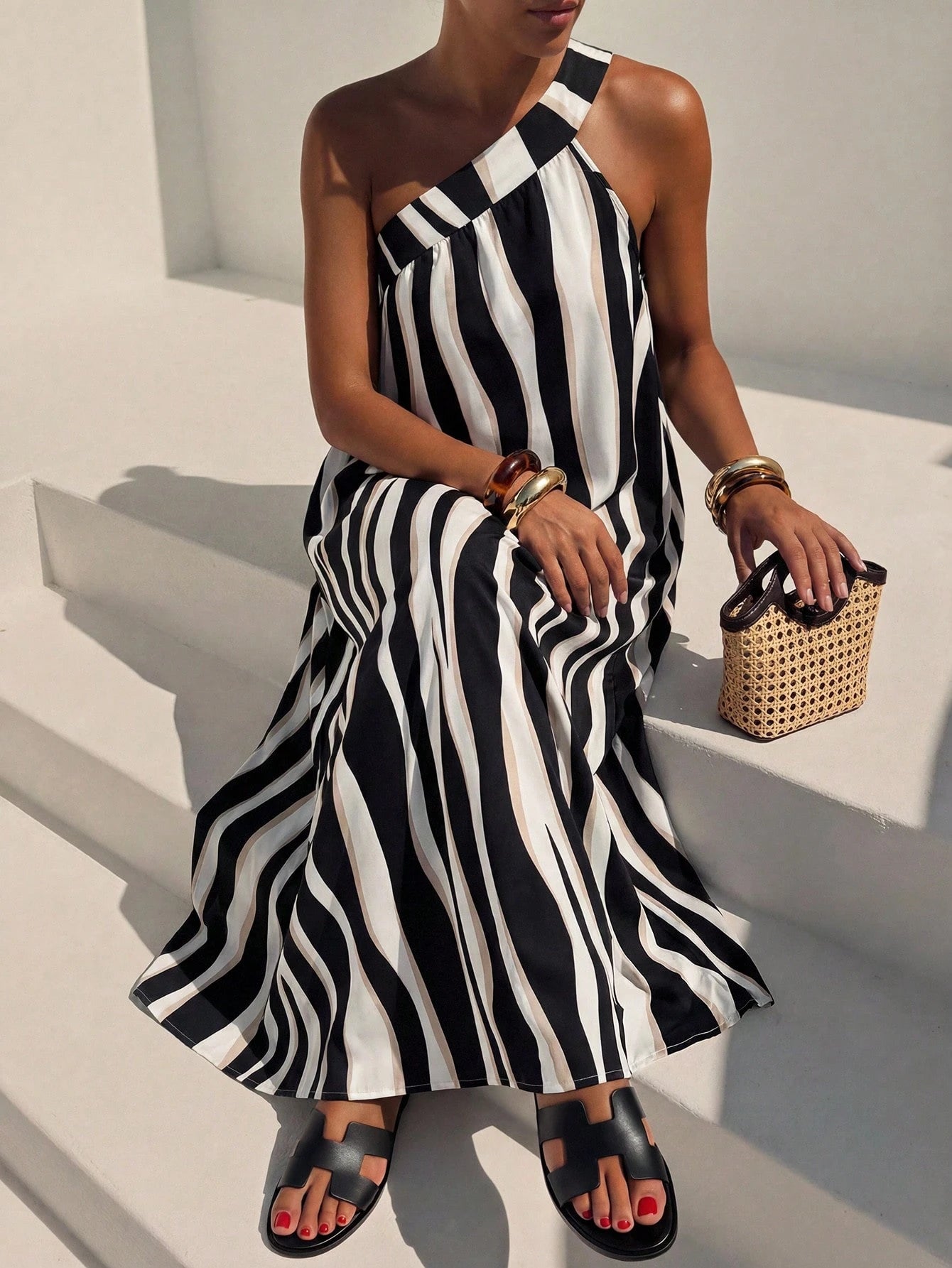 Woman wearing a black and white striped dress sitting on a white bench.